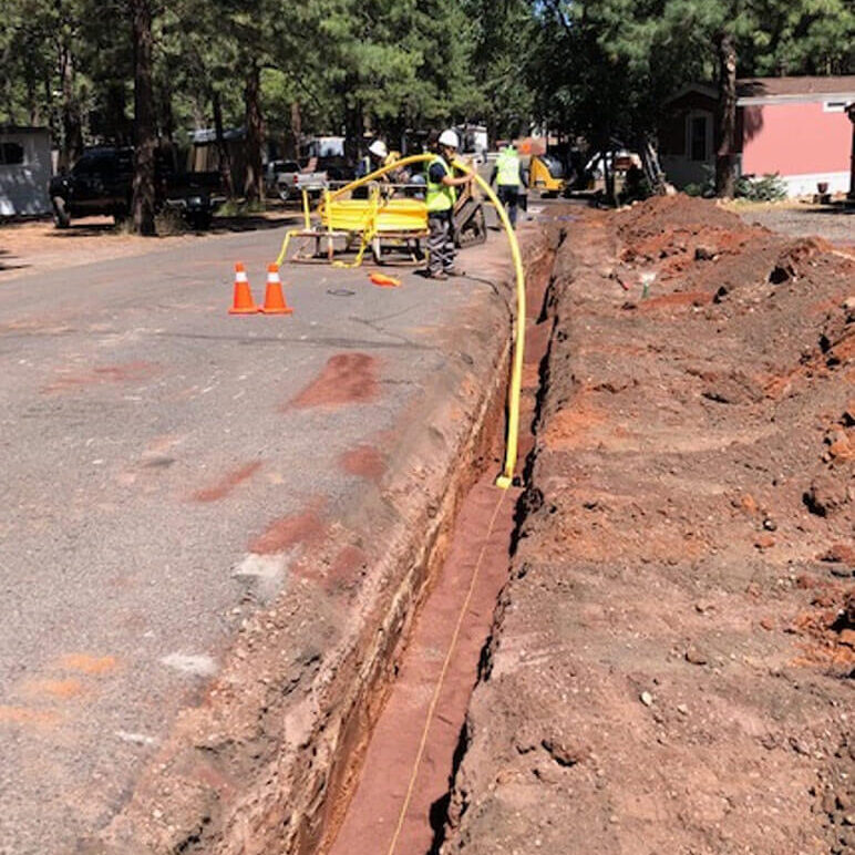 Photo of an underground natural gas pipe being installed in a trench, showing Liberty-Gandy natural gas line installation