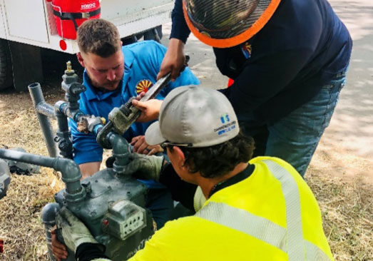 Photo of the Liberty-Gandy emergency pipeline repair team in action; several men working together in a trench